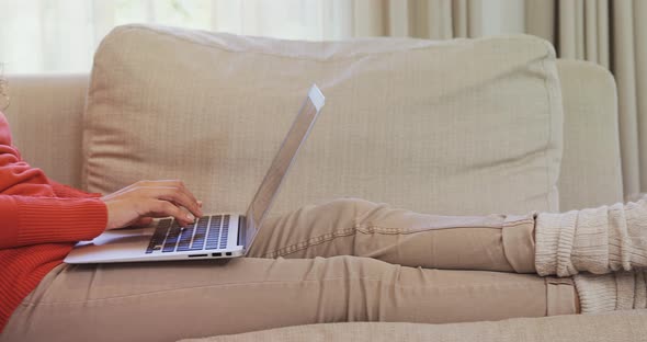 Thoughtful woman sitting on sofa working on her laptop 4K 4k