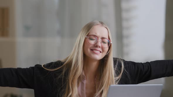 Caucasian Business Woman Girl Blonde in Glasses Sits at Table Looking Into Laptop Opens Mouth Shock