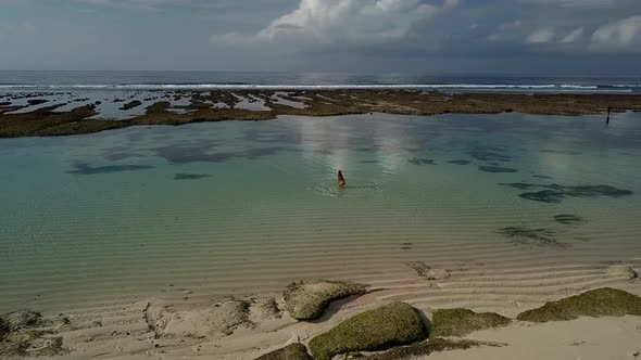 Woman in a Bikini Playing with Water on the Beach