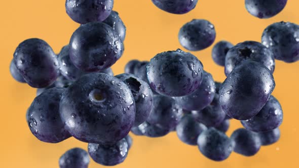 Flying of Blueberries in Pale Orange Background