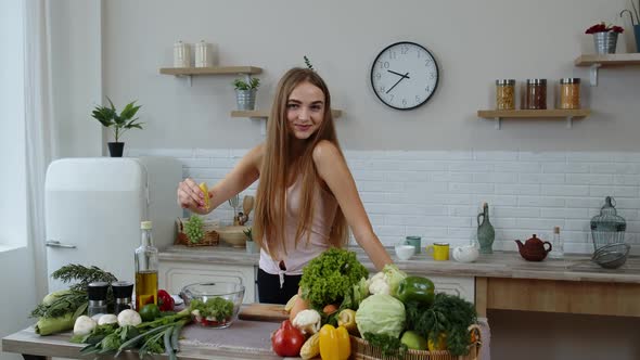 Vegan Girl in Kitchen Adding Lemon Juice To Salad with Raw Vegetables. Weight Loss and Diet Concept