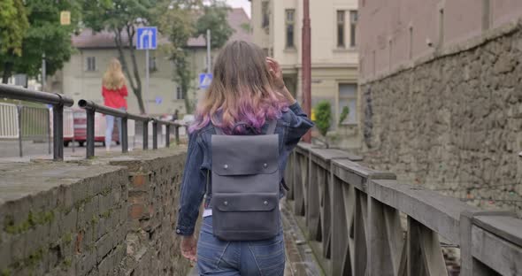 Teenager Girl Walking Across Vintage Wooden Bridge in Old Tourist Town, Back View