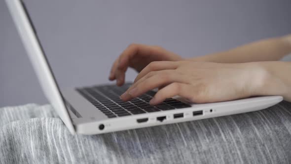 The Girl Comes To the Bed Sits on It and Prints a Message on a Laptop Communicates in Social