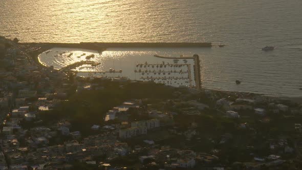 Harbor by Coast Town with Boats Separated from Sea by Breakwater in Sunset Glow