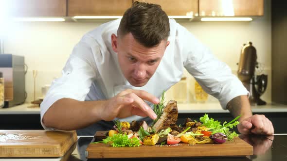 chef decorates sprig of Basil delicious dish with grilled meat and vegetables .