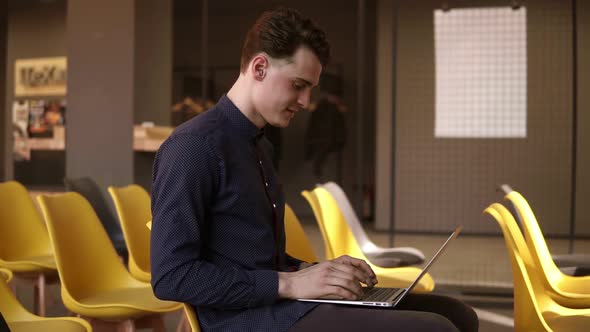 Young Attractive Male Typing Something on a Laptop