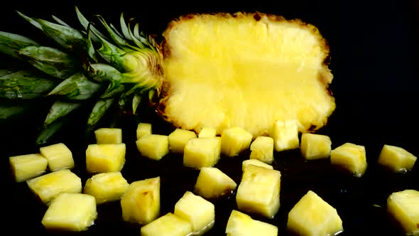 Falling juicy pieces of pineapple on a black background. Slow motion.