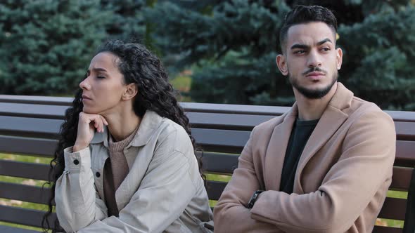 Offended Young Hispanic Couple Looking Different Direction Sitting on Bench in Autumn Park Annoyed