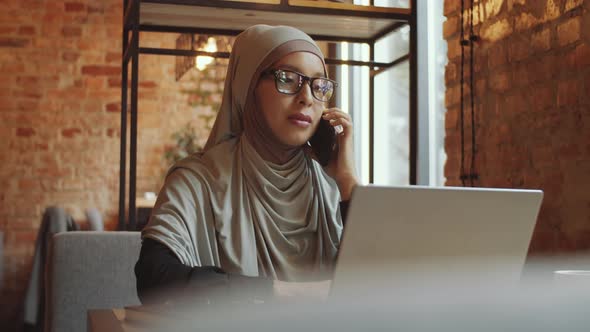 Businesswoman in Hijab Speaking on Cell Phone in Cafe