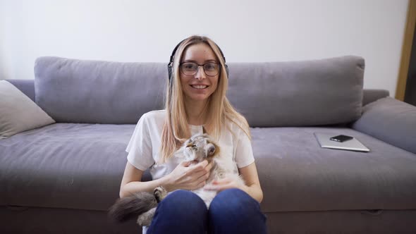Webcam View Woman in Headphones Hugs Cat Shoots Video for Blog with Pet