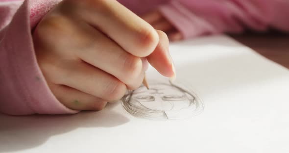 Young Woman Artist Sitting and Painting Man Portrait on White Paper Using a Pencil in Workshop