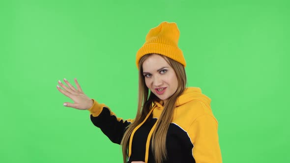 Portrait of Modern Girl in Yellow Hat Is Talking and Pointing Side Hand for Something, Copy Space