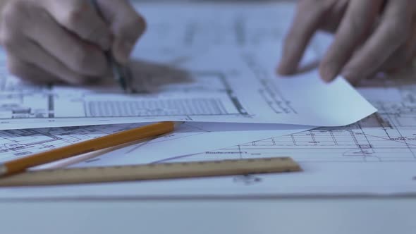 Male architect checking building layout, making notes and calculations, design