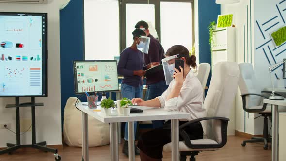Freelancer with Mask Talking on Mobile Phone in Fron of Computer