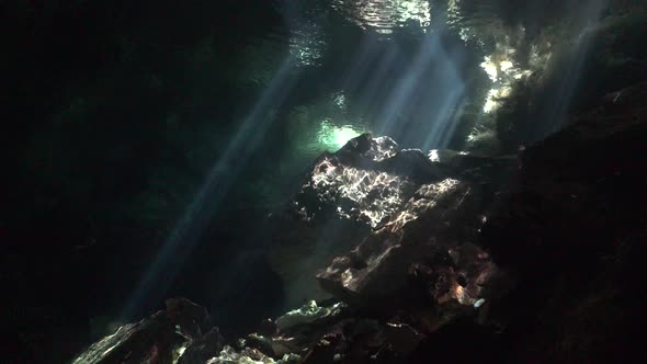 Sun rays shining through water surface onto rock formation in Cenote Chikin Ha cave system Yucatan M