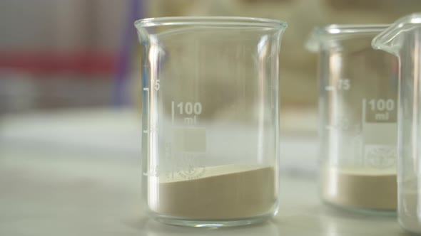 Science beakers partially filled with white powder chemicals ready for research