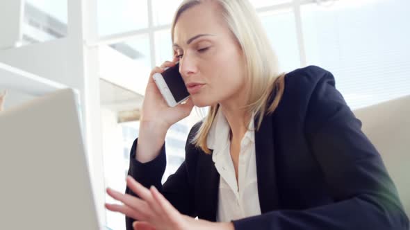 Businesswoman talking on the mobile phone at her desk