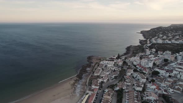 Seaside houses overlooking ocean. Small waves washing on Praia da Luz beach, Algarve