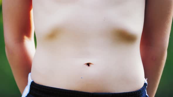 Boy's stomach breathing. Close-up of teenager's body in shorts isolated on green background