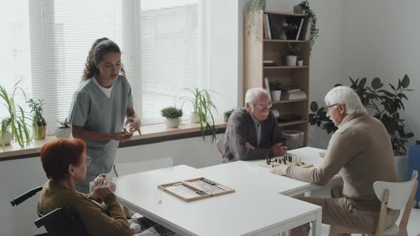 Nurse Giving Pills to Seniors at Nursing Home