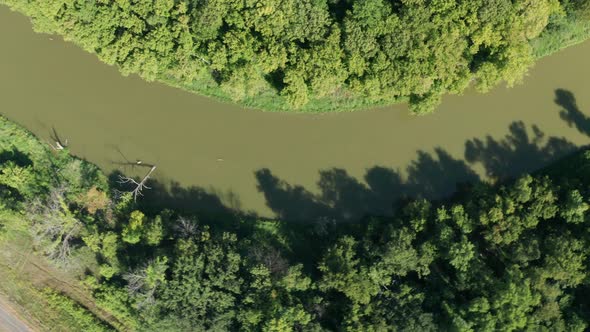 Aerial top down flying over river bend with muddy murky water