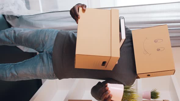 Vertical Unrecognizable African American Man with Cardboard Box on the Head and Plant in the Hand