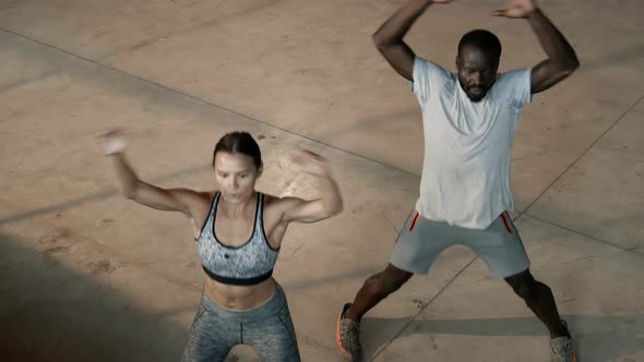 Fitness. Fit couple doing jumping jack exercise at gym indoors