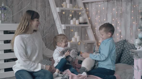 Mother in Sweater Watches Son and Daughter Play with Toys