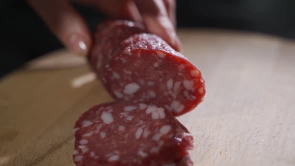 Man Cuts Into Thin Slices Fatty Sausage. Shooting Closeup. Chef Cutting Salami with a Knife