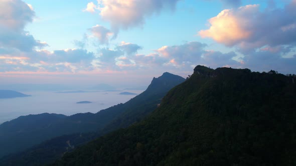 The rays of the sun shine through the clouds into the misty above the mountains in the morning