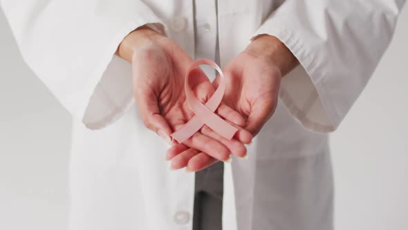 Video of biracial female doctor holding pink breast cancer ribbon