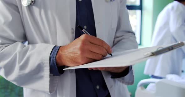 Male doctor writing on clipboard in the ward 4k