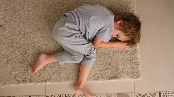 Child is Bored Lying at Home on the Floor