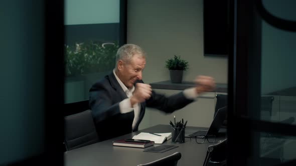 Businessman At Laptop Shaking Fists Celebrating Business Success In Office