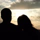 Silhouettes of a Young Couple at Sunset. A Woman Puts Her Head on Her Boyfriend's Shoulder. - VideoHive Item for Sale
