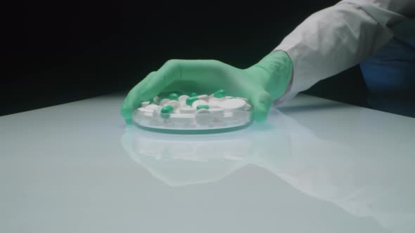 Pharmaceutical Lab Technician Putting Dish with Medicines on Table