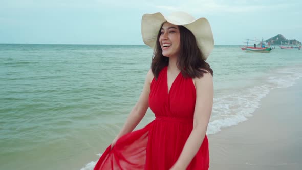 slow-motion of cheerful woman in red dress walking on the sea beach