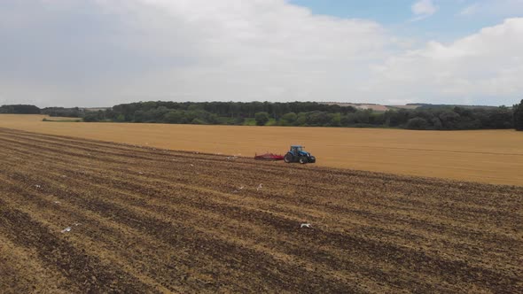 Aerial drone view of white storks feeding on plowed by tractor agricultural field.