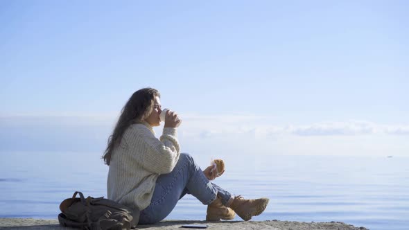 Woman Drinks Coffee Sitting on Sea Pier