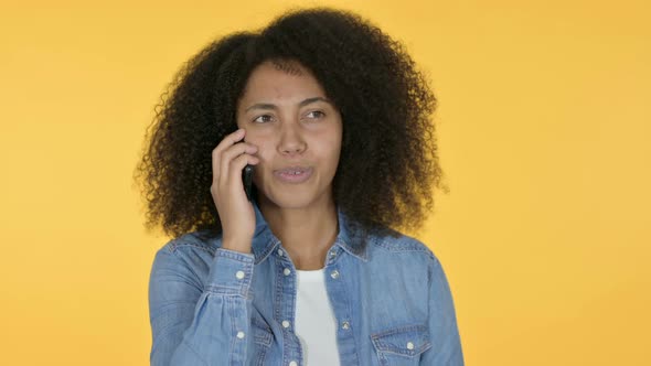 African Woman Talking on Smartphone, Yellow Background 