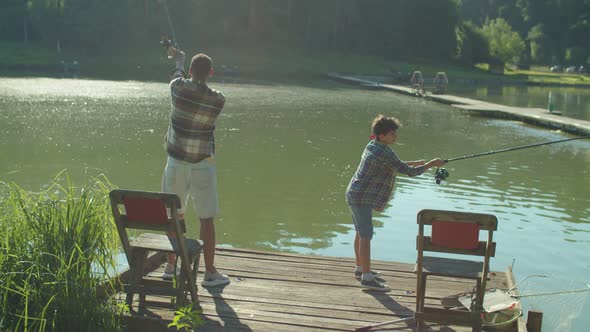 Preadolescent Boy and Black Father Casting Fishing Rods During Fishing on Pond