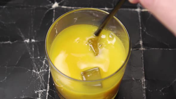 Cocktail with orange yellow fruit juice and ice cubes in a glass