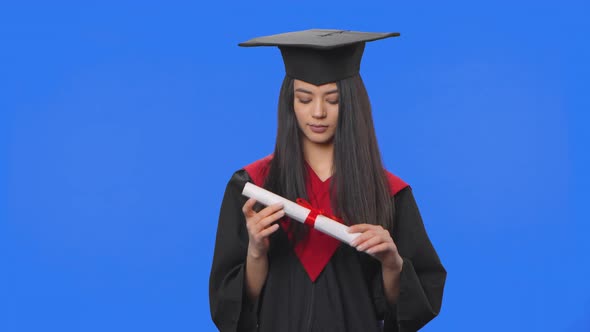 Portrait of Female Student in Cap and Gown Graduation Costume Holding Diploma and Then Throwing It