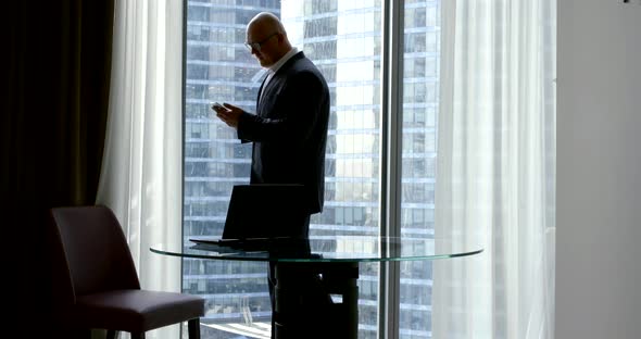 Businessman Is Reading Message in Smartphone and Calling, Walking in Office Room in Daytime