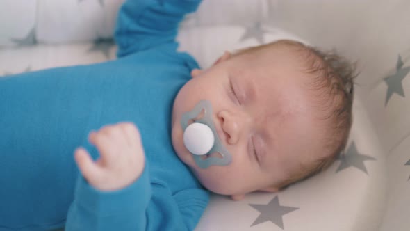 Newborn Baby Waves Hands Sleeping in Cocoon at Home Closeup