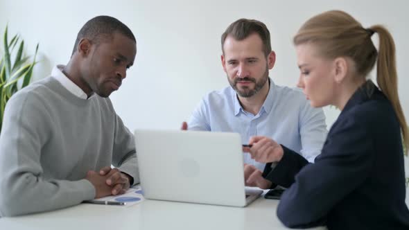 Male and Female Business People Having Discussion While Using Laptop in Office