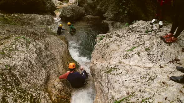 Aerial view of a group of people canyoning and sliding through rocks in river.