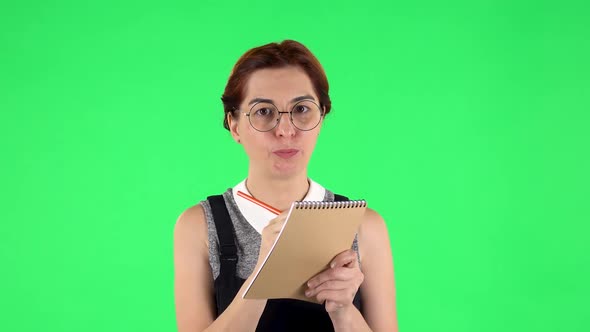 Portrait of Funny Girl in Round Glasses Is Thinking, Then Angrily Writing with Pencil in Notebook