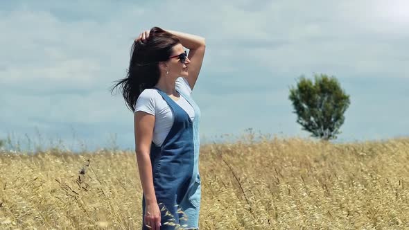 Attractive Young Woman Enjoying Magnificent Nature Standing in Field of Wheat or Dried Grass