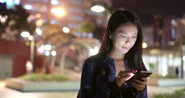 Woman look at smart phone in city at night